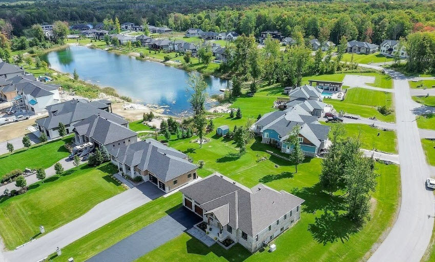 Aerial view of detached homes and landscaped lots around a pond in Greely